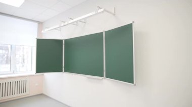 Boş sınıf beyaz duvara monte edilmiş temiz modern bir tahta gösteriyor. Eğitim alanı, parlak akademik içişlerinde bir sonraki ders için hazırlanıyor