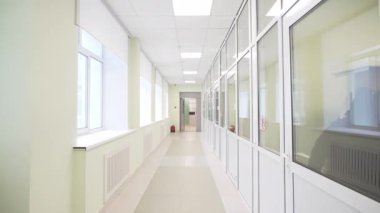 Geniş ışıklı koridor cam kapılar ve minimalist tavanın altındaki duvarlar boyunca uzanıyor. Büyük pencereler modern alanı doğal ışıkla doldurur