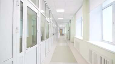 Gün ışığında parlak uzun koridor ve geniş pencereli modern minimalist tasarım. Temiz modern iç mimari beyaz duvarlar ve kapılar içerir