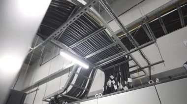 Endüstriyel hortumlar fabrika girişinin üzerinden geçiyor. Metal kirişler, çalışma günlerinde kabloyu işçilerin üzerinde güvenli bir şekilde tutar.