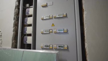 Yeni binanın tamamlanmamış duvarında düğmeleri olan büyük bir santral. Yerleşimcilere enerji sağlamak için modern yüksek katlı elektrik ağı