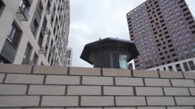 Çatıdaki pervane yüksek binalar arasında tuğla yüksekliğinde. Gökyüzü altında küçük balkonları olan yüksek binaları olan modern yerleşim yerleri.