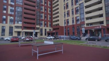 Modern yerleşim alanının içindeki iç avluda. Tenis kortu ve araba park alanı koyu ve aydınlık cepheli yüksek binaların yanında.