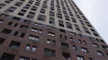 Koyu ve açık dış açılı alçak açılı uzun, modern bir apartman. Pencereler ve balkonlar tekrarlanan desenlere göre düzenlenmiş