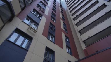 Pürüzsüz geometrik tasarım alçak açılı çekimle yüksek apartman kompleksi. Yukarıdaki açı, binaların yüksekliğini ve sayısız pencereyi vurguluyor