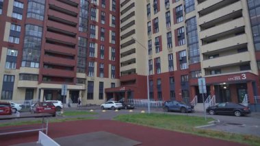 Çağdaş konut kompleksinin merkezi avlusu. Tenis kortu ve gökyüzü altında karanlık ve aydınlık cephelerin karıştığı binaların alanlarında park yerleri