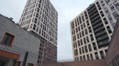 Güneşli bir günde aydınlık ve karanlık cepheli modern gökdelenler. Demir parmaklıklı mason bariyeri şehir manzarasını güçlendiriyor