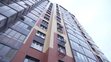 Bulutlu, alçak açılı, modern tasarım kuleleri olan bir bina. Camdan balkonları ve karanlık cepheleri olan yüksek binalar.