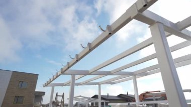 Çadırın metal çerçevesi, gökyüzünün altında tüylü bulutlarla benekli duruyor. Pürüzsüz yapısal çizgiler, açık havada canlı öğrenme alanı vaat ediyor.