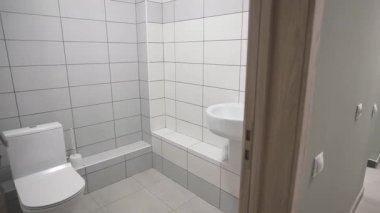 Tuvalette parlak fayanslar modern tuvalet ve seramik leğen var. Işık tasarımı basitliği yansıtır. Taze düzen rahatlığı vurgular