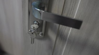 Parlak krom kapı koluna yeni bir anahtar takılmış. Temiz ahşap yüzeye zarafet katıyor. Güvenli kilit sistemi koruma ve rahatlık sağlar.