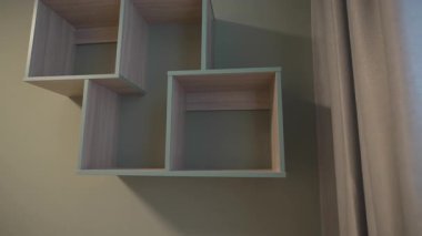 Ders kitapları için geometrik raf ve yer tasarrufu asimetrik düzende dekoratif ögeler. Modern yurt dekorunda ahşap aksanlı paneller