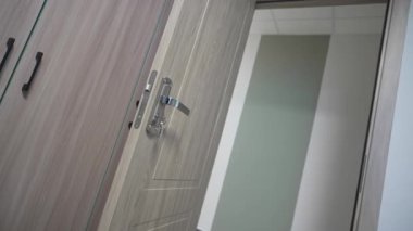 Açık kapı girişini davet etmek, yurdun içini bir anlığına gösterir. Kilit açılmamış pirinç anahtarla parıldıyor. Güvenlik ve kişisel alan vaat ediyor.