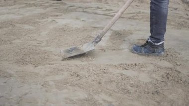 İnşaat işçisi sağlam çelik kürekle çakılları dikkatlice yere serdi. Elle şekillendirme, inşaat tabanı için bile sıkıştırma yüzeyi