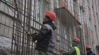 ALMATY, KAZAKHSTAN - 19 Şubat 2025: sağlam miğfer odaklı işçi güçlendirilmiş yapıya sahip demiri demirler. Güçlü eller çelik parçayı itina ve özenle manevra ettirir.