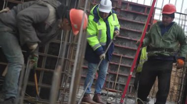 ALMATY, KAZAKHSTAN - 19 Şubat 2025: İnşaat işçileri malzemelerle birlikte inşaat alanında koşturuyorlar. Takım çalışması hızlı ve organize inşaat akışını sağlıyor