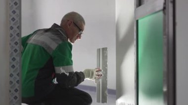 ALMATY, KAZAKHSTAN - 19 Şubat 2025: spatula ile pürüzsüz gözlük takan adam. Hassas hareketler kusursuz alçı oluşturur. Profesyonel görünümü garantiye alır.