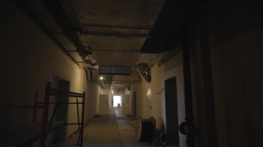 Yükselen tavanlı koridor görünür havalandırma borularını gösteriyor. İşlenmemiş alan devam eden bir iş olduğunu gösteriyor. Boyanmamış duvarlar ve kanallar korkunç bir hava yaratıyor.