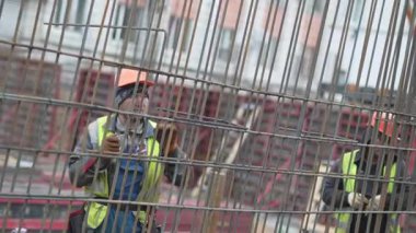 ALMATY, KAZAKHSTAN - 19 Şubat 2025: İnşaatçı çelik çubukları sağlam temeller için beton demire çevirir. Kesin eylemler yapının dayanıklılığını ve istikrarını sağlar