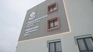 ALMATY, KAZAKHSTAN - 19 Şubat 2025: Çocuk bölümü binası bulutlu gökyüzünün altında gri bir cephe gösteriyor. Stark renkleri bulutlu havayla zıtlaşır ve ciddi bir ruh hali yaratır