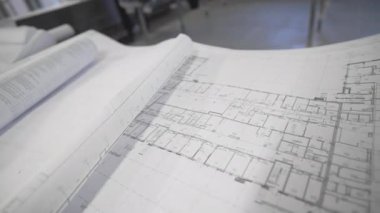 Açık planlar taslak masa boyunca uzanıyor. Mimari düzen net çizgiler ve bina planlarını gösteriyor. Ayrıntılı inşaat çizimleri