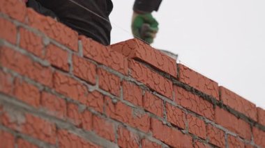 İnşaatçı paltoları betonla kaplanmış. Dikkatli teknik, yükselen duvarın profesyonel rehberlik altında dayanmasını ve hizalanmasını sağlar.