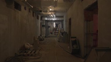 İnşaat alanındaki genişletilmiş koridor kablo kanalları ve düzensiz aletlerle dolu. Açığa çıkan tavan, açık havalandırmayı gösterir.