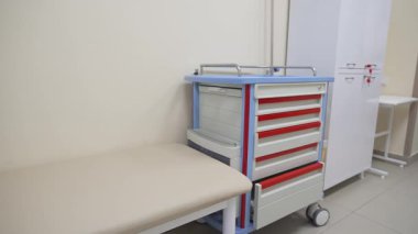 Aydınlatılmış prosedür odasında çekmecelerin koçu ve tekerlekli sandığı. Hasta hizmetleri için mobilyalarla modern hastane içi