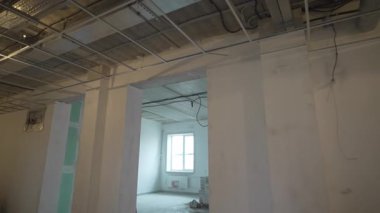 Tavanda ve sütunda şebeke leşi olan geniş, yenilenmiş bir yer. Eski bina restorasyonu şantiyede çalışıyor. Bitmemiş ofis