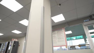 Kamu binasının lobisinde alçıpan sütun ve kapalı devre kamera var. Sağlık hizmetlerinde izleme aracı ve mimari detay