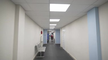 Modern hastanede koltukları ve parlak ışıkları olan uzun bir koridor. Sağlık merkezinin içinde beyaz duvarlı lobi. Tıbbi hizmet