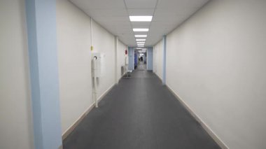Modern hastanede kapıları ve lambaları olan boş bir koridor. Klinik binasının içinde duvarlar olan uzun bir koridor. Ofis merkezi içi