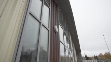 Temiz minimalist cephede panoramik cam pencereler yumuşak bulutlu gökyüzünü yansıtır. Pürüzsüz modern yüzey sakin mimari varlığı arttırır