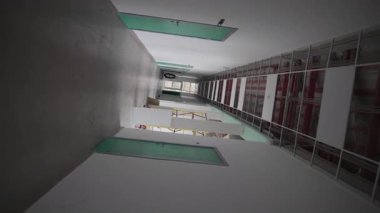 Pürüzsüz dairesel kamera hareketi, temiz koridorun geniş pencereli plastik filmle bittiğini gösteriyor. Parlak yüzeyler yenilemeyi yansıtıyor