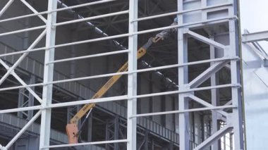 ALMATY, KAZAKHSTAN - 17 Ekim 2024: inşaat alanındaki metal şebekenin arkasındaki hidrolik vinç kaldırma. Kargo kaldırma makinesi tamamlanmamış depolama pavyonunda ağır ögelerle çalışır