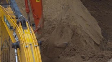 ALMATY, KAZAKHSTAN - 17 Ekim 2024: Sarı çapa kovası toprak yığınını yakın çekime taşıyor. Güçlü kazıcı inşaat sahasında hendek kazıyor. İnşa makinesi