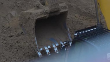 ALMATY, KAZAKHSTAN - 17 Ekim 2024: Kirli metal kazıcı kovası yakın çekime giriyor. İnşaat alanındaki hendekte büyük çapta toprak taşıyıcı çalışıyor.