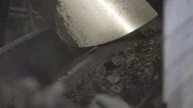 Lastik parçaları kavisli çelik oluktan kayıyor. Taşıyıcı lastiği son öğütücüye yönlendiriyor. Paraşüt titreşir ve parçaları dönen bıçaklara yem eder.