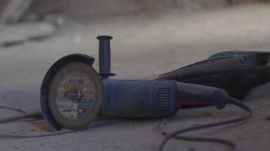 ALMATY, KAZAKHSTAN - Nisan 04 2025: Atölyenin kirli zemininde kablolu elektrikli testere. İnşaat alanındaki tozlu yüzeyde soldan malzeme kesme aracı