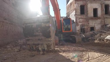 ALMATY, KAZAKHSTAN - APRIL 04 2025: Yıkım alanındaki yıkıntıların arasında kirli kova ile modern tırtıl kazıcı. Güçlü buldozer atıkları temizliyor.