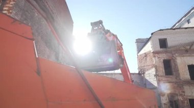 ALMATY, KAZAKHSTAN - Nisan 04 2025: Kazı kovası yıkım alanındaki kamyon römorkuna toprak yüklüyor. İnşaat makineleri şehir ortamında toprak temizleme yeri ile çalışır