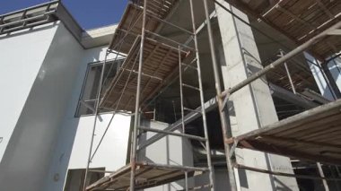İnşaat alanının ön cephesinde ahşap zemin ve merdivenleri olan iskeleler. İşçi erişimi için çerçeve düşük açılı çekim