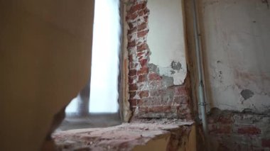 Çatlak alçı yüzeyin altında gizlenmiş eski kırılgan tuğlaları ortaya çıkarıyor. Plastik pencere, eski mimari ve modernliğin karşıtlığını yaratır