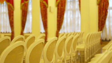 Geniş ve parlak salon koltukları yastıklı, düzgün sıralanmış sandalyelerle dolu. Doğal ışık, odaya hoş bir atmosfer sağlar.