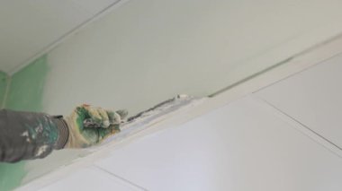 Tecrübeli işçiler geniş malayla duvarlara alçı yayar. Kirli üniforma, kusursuz el altında temiz yüzeye zıt düşer.