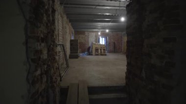 Kırılgan duvarların soyulduğu koridor boyunca ilerlemek çiğ tuğla odasını ortaya çıkarır. Küçük pencere eksikliğin atmosferini vurgular