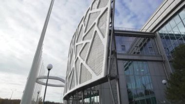 Orijinal cam cephe parlak bahar güneşi altında parıldıyor. Dekoratif ağ paneli inşaata ritim derinliği ve mimari cazibe ekler