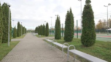 Arenanın yanındaki banklarla ve ağaçlarla süslenmiş rahat yürüyüş yolu. Zincir bağlantısı tasarımı insanların oyunları dışarıdan rastgele izlemelerine olanak sağlıyor