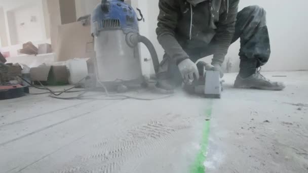 男は壁のシャーザーで床下暖房をインストールするためのコンクリート床に凹部を作ります — ストック動画