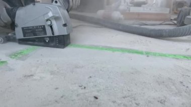 Bir adam beton zeminde duvar kovalayıcısıyla yer altı ısıtması kurmak için ara veriyor. Yakın plan. 4K filmi
